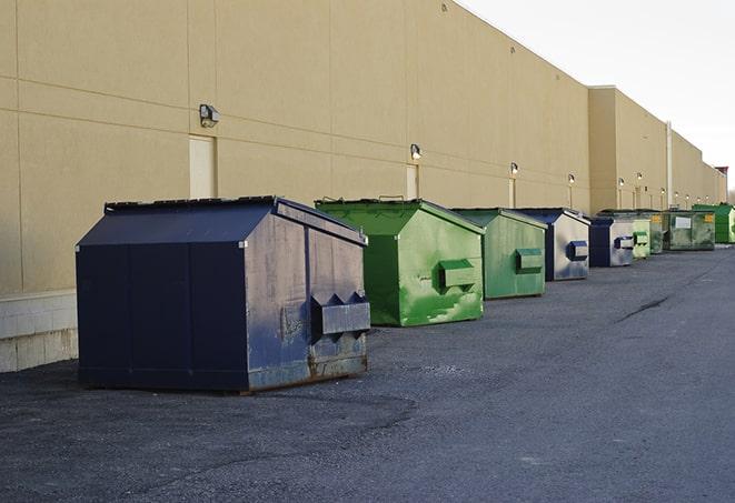 a series of colorful, utilitarian dumpsters deployed in a construction site in Bellerose, NY